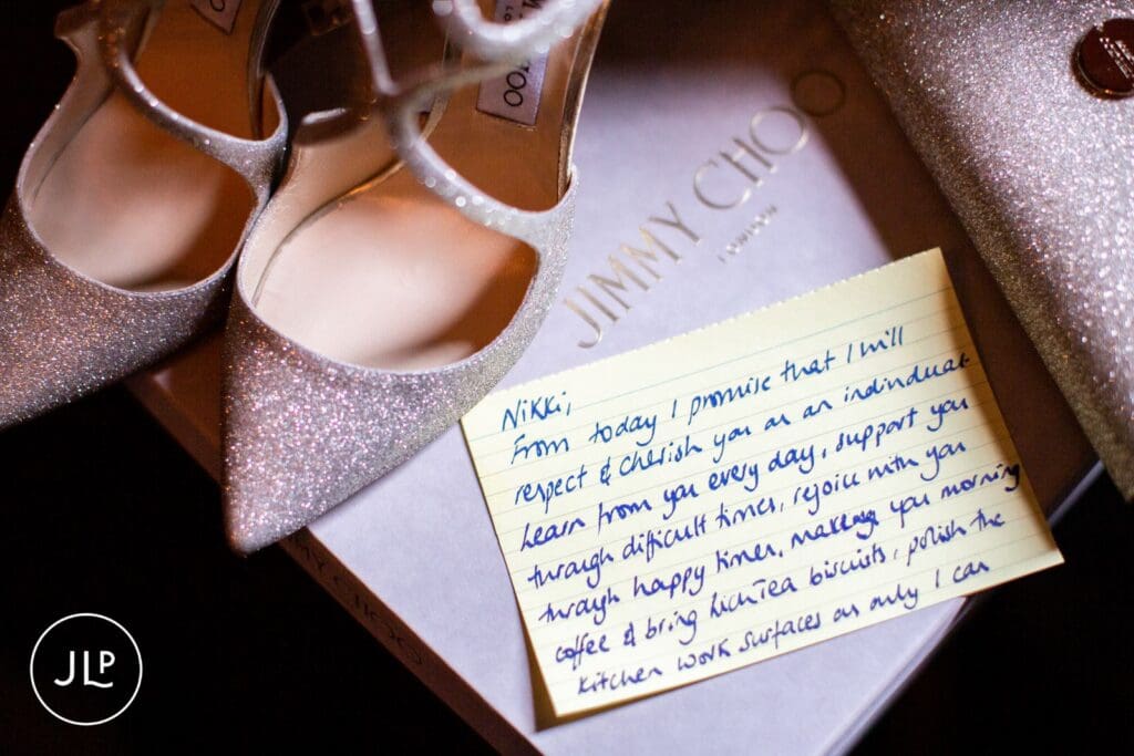 A handwritten card next to silver Jimmy Choo shoes captured by a luxury wedding photographer UK.