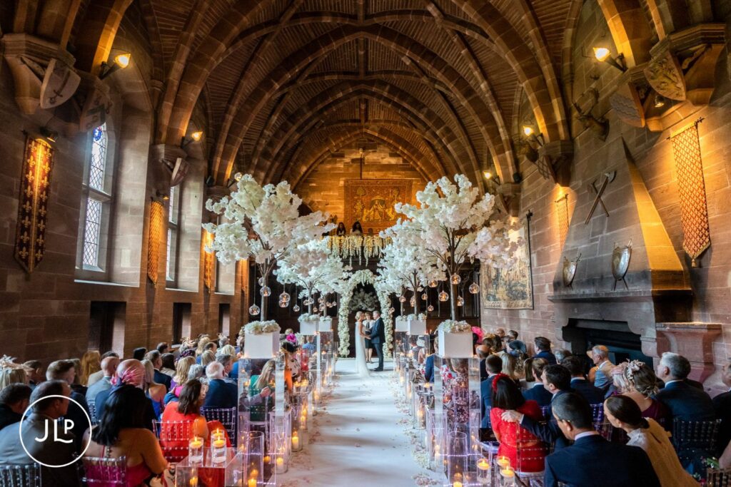 Wide shot of a luxury castle wedding ceremony taking place inside the spectacular Great Hall.