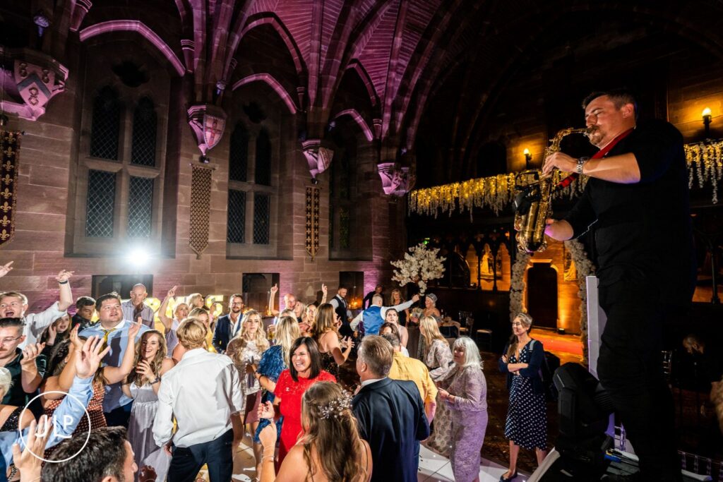 A live saxophonist performing on a raised platform for a packed wedding dance floor in Cheshire.