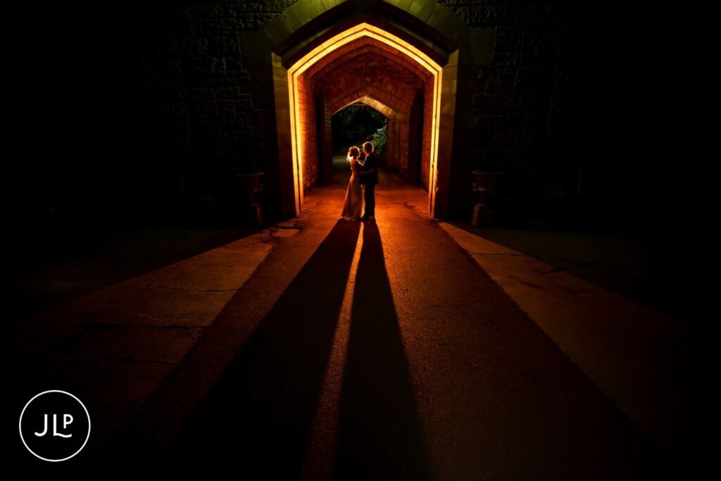 Romantic backlit silhouette portrait of a bride and groom during an elegant castle wedding night shoot.