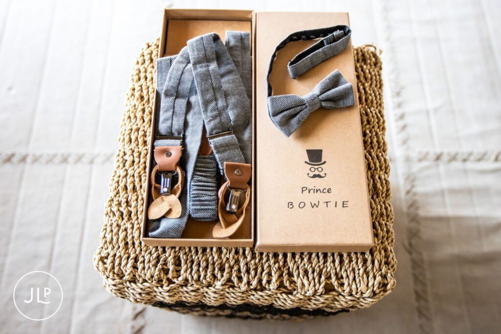 Close-up of a groom’s bow tie and suspenders inside a box, documented by an Africa wedding photographer.