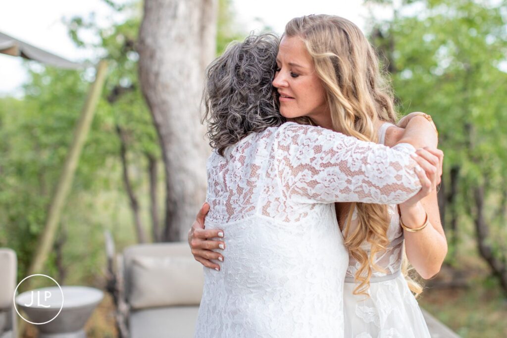 Candid safari wedding photography of an emotional hug between the bride and a family member on a luxury deck.