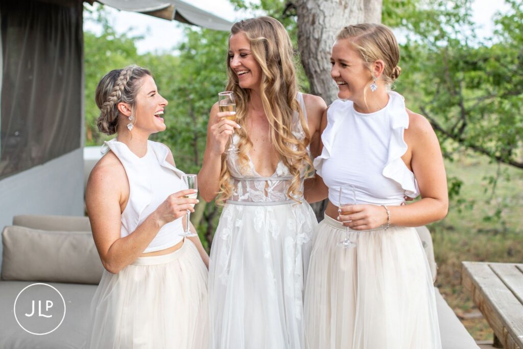 A bride in her elegant gown laughs with bridesmaids during a luxury safari wedding Botswana celebration.