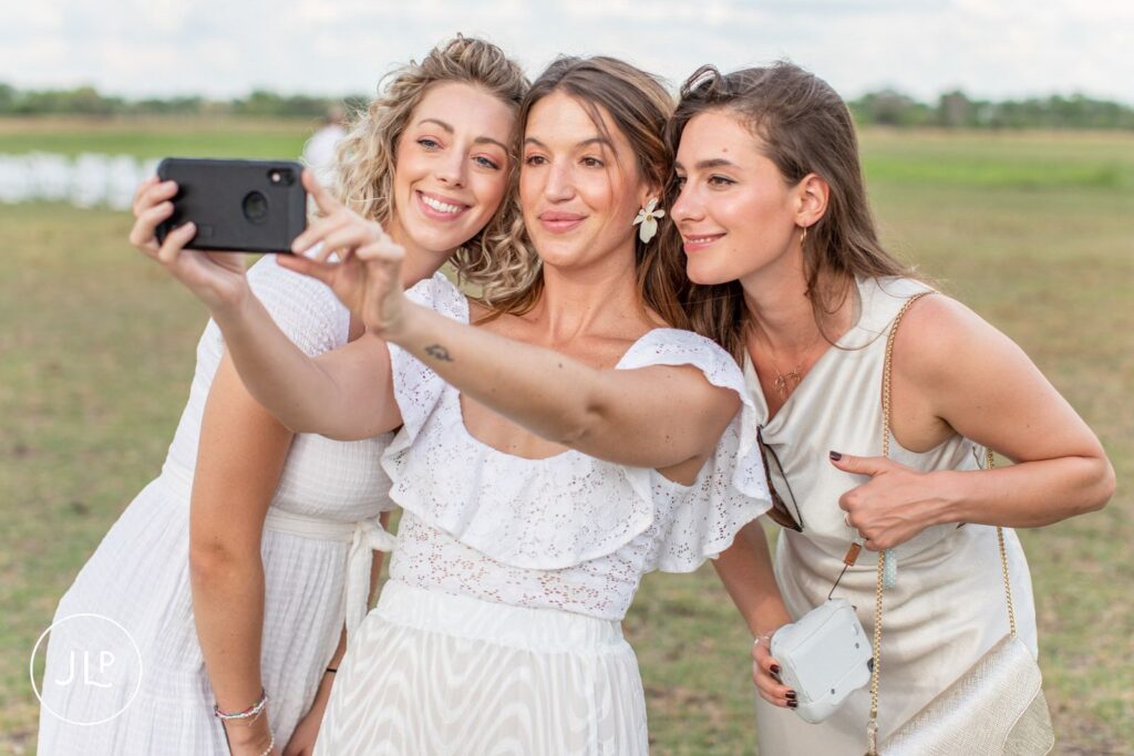 Candid safari wedding photography of guests smiling and taking a selfie together on the open plains.