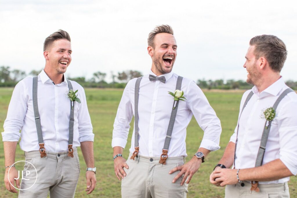 Groomsmen share a laugh together during a relaxed outdoor destination wedding photographer Africa session.