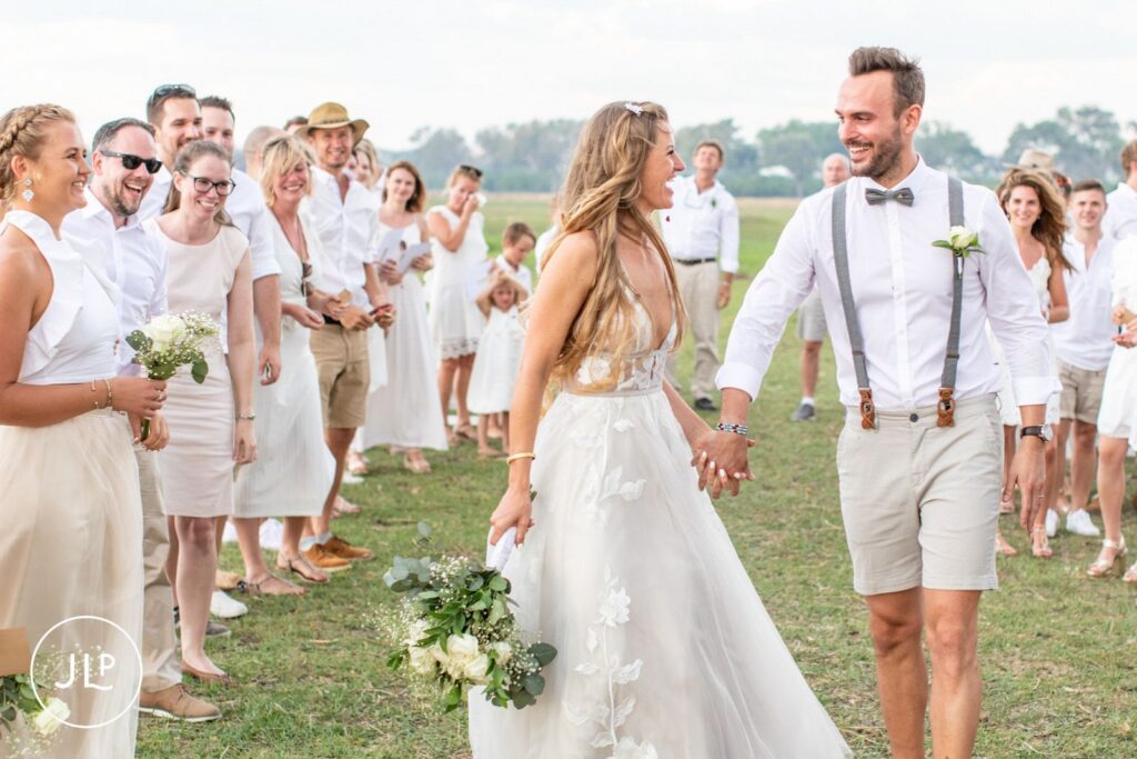 A happy bride and groom walking up the aisle hand-in-hand during their luxury safari wedding Botswana.