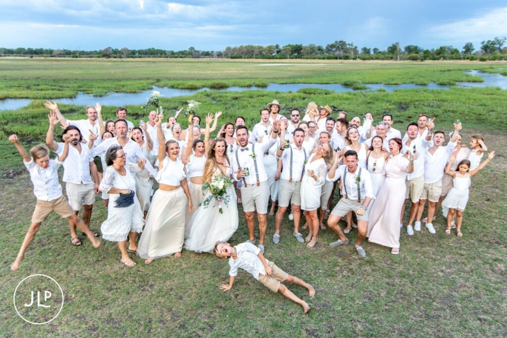 Candid safari wedding photography of the entire wedding group cheering together in the Okavango Delta.