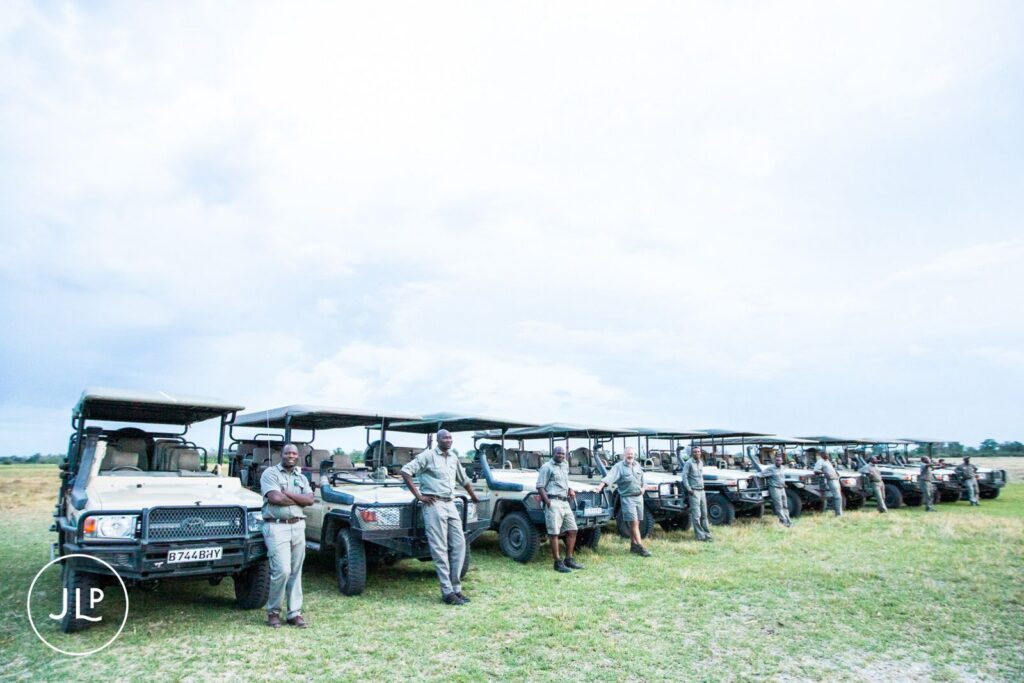 A line of safari vehicles and park guides captured by a professional Botswana safari wedding photographer.