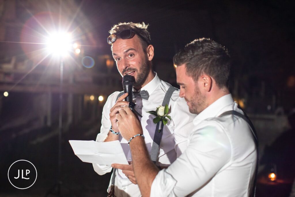 Groomsmen speaking into a microphone at night, by a Botswana destination wedding photographer.
