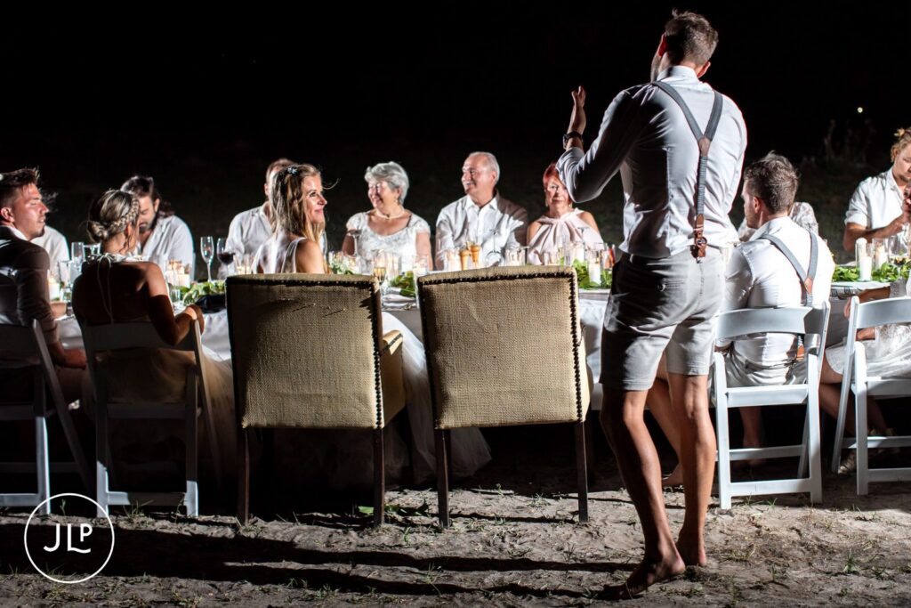 A guest stands to give a speech at an outdoor luxury safari wedding Botswana reception dinner.