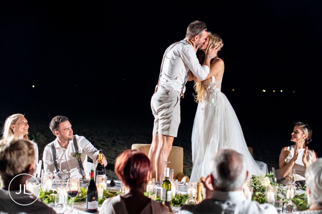A bride and groom sharing a kiss during dinner, captured by a professional Botswana destination wedding photographer.