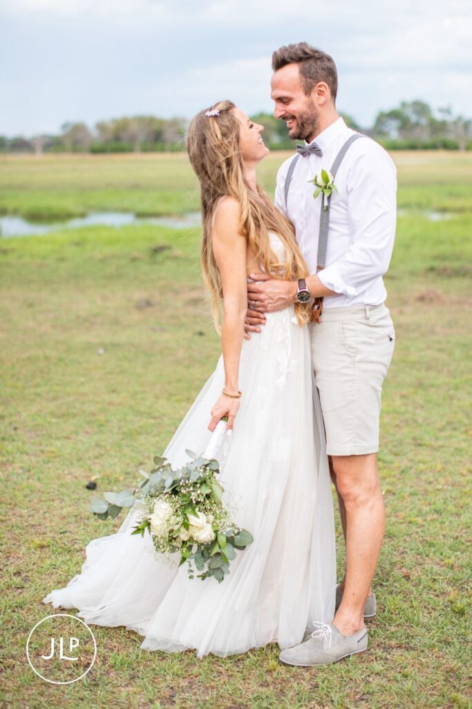 Natural wedding photography Botswana style of a bride and groom smiling at each other on the grassy plains.