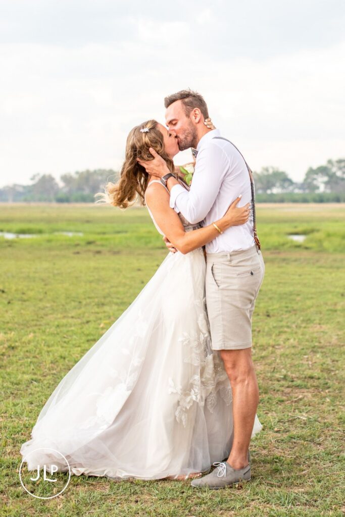 Safari wedding photographer Botswana shot of a romantic newlywed kiss on the delta floodplains.