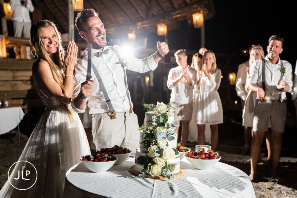 A joyful couple cutting their white floral wedding cake, captured by a safari wedding photographer Botswana.