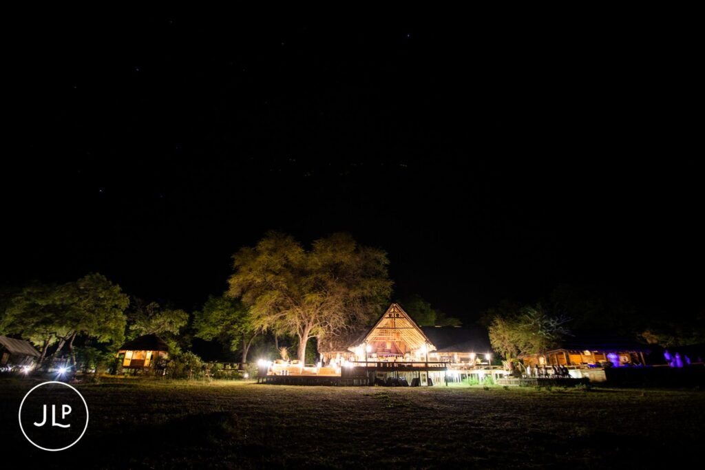 Breathtaking Okavango Delta wedding photographer wide shot of a luxury safari lodge illuminated at night.
