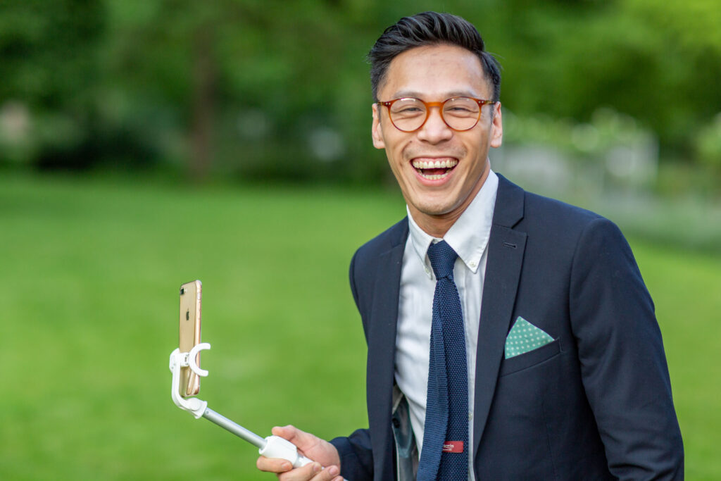 Laughing wedding guest with selfie stick