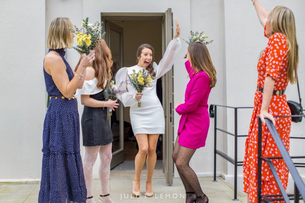 a very excited bride with her bouquet surrounded by her bridesmaids on her way to the chapel to get married.