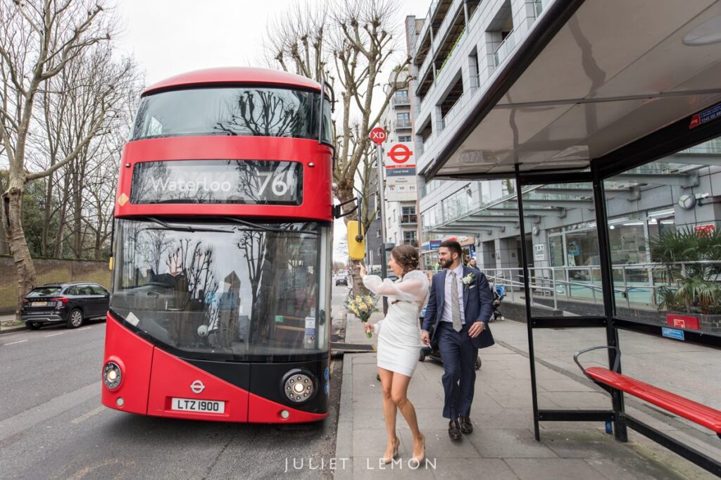 bride and groom waving to red London bus in Islington on way to their wedding reception