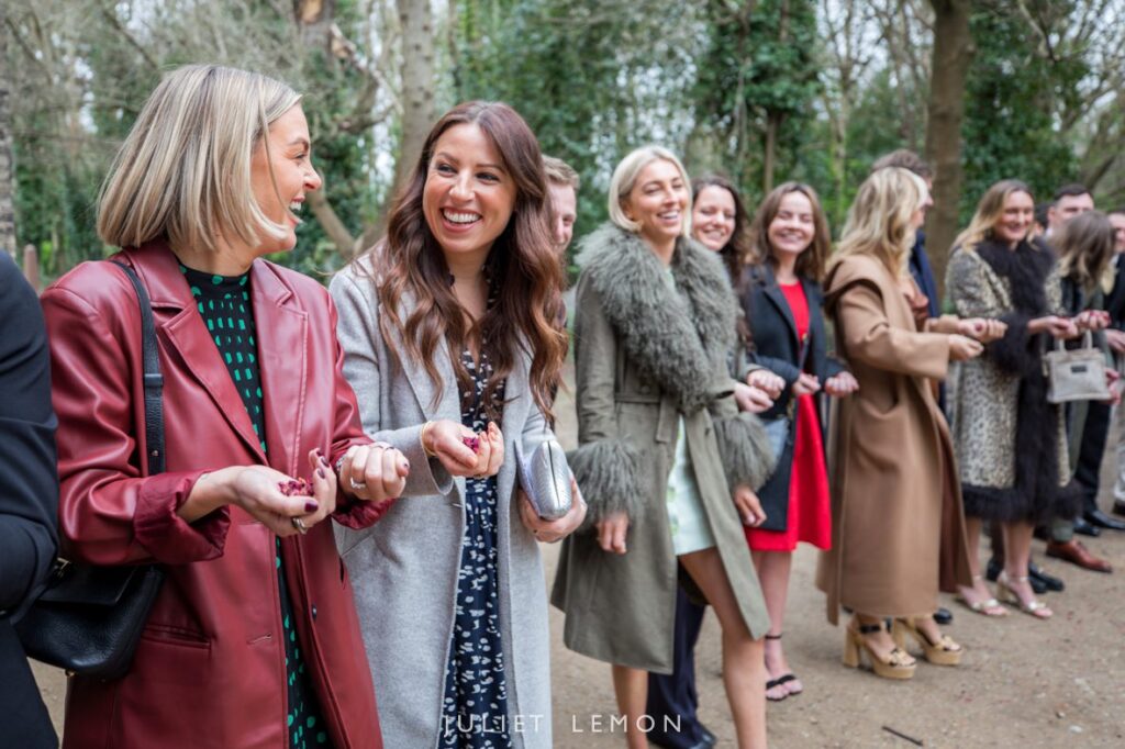 Female guests in winter coats prepare handfuls of red confetti at Abney Park