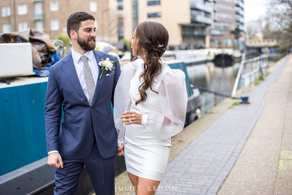 Abney Park wedding venue photography: couple walking along the canal towpath with city architecture.