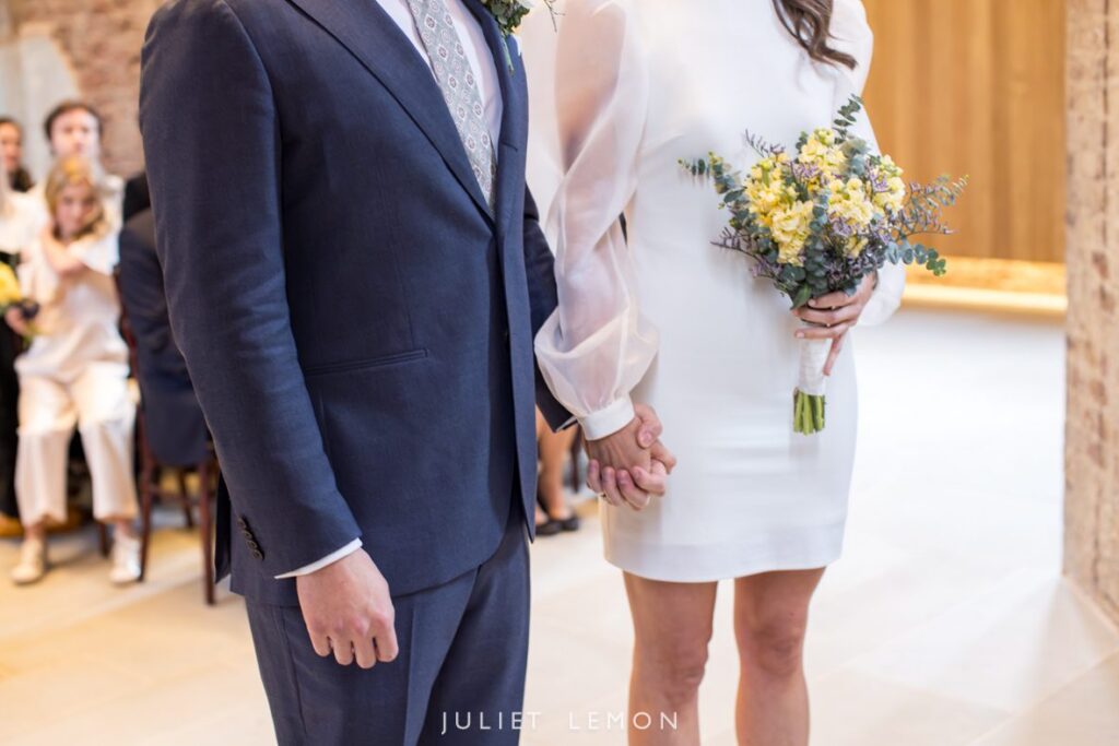 Close-up of the couple holding hands at the altar, captured by a London wedding photographer.