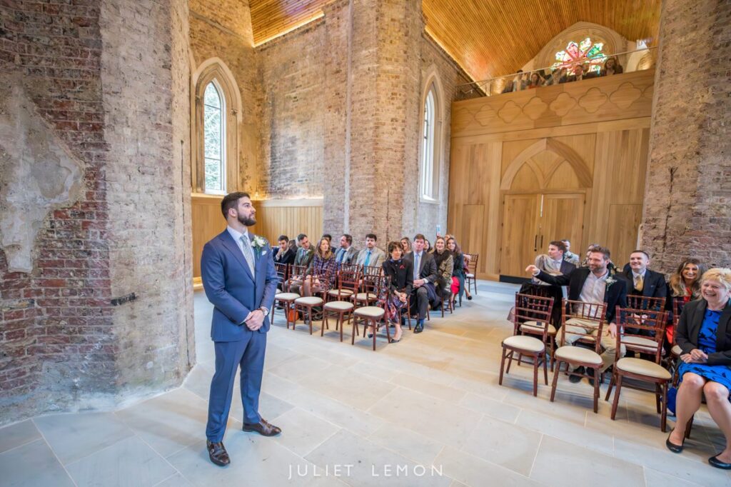 The groom waits at the altar, captured by a Stoke Newington wedding photographer at Abney Park Chapel.