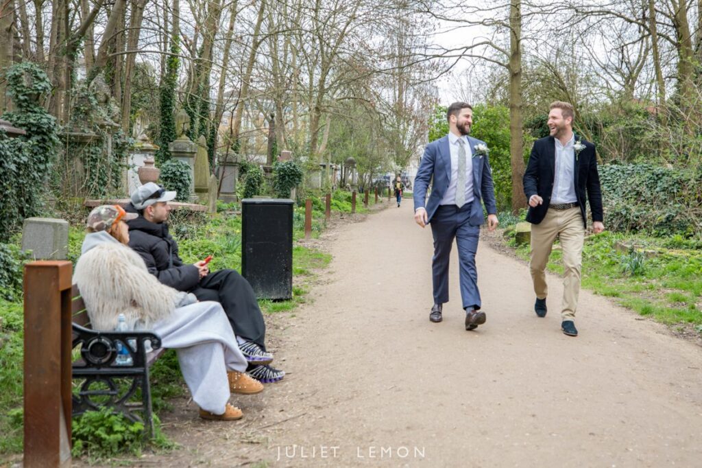 The groom and best man walk through the park, a classic shot from a London wedding photographer.
