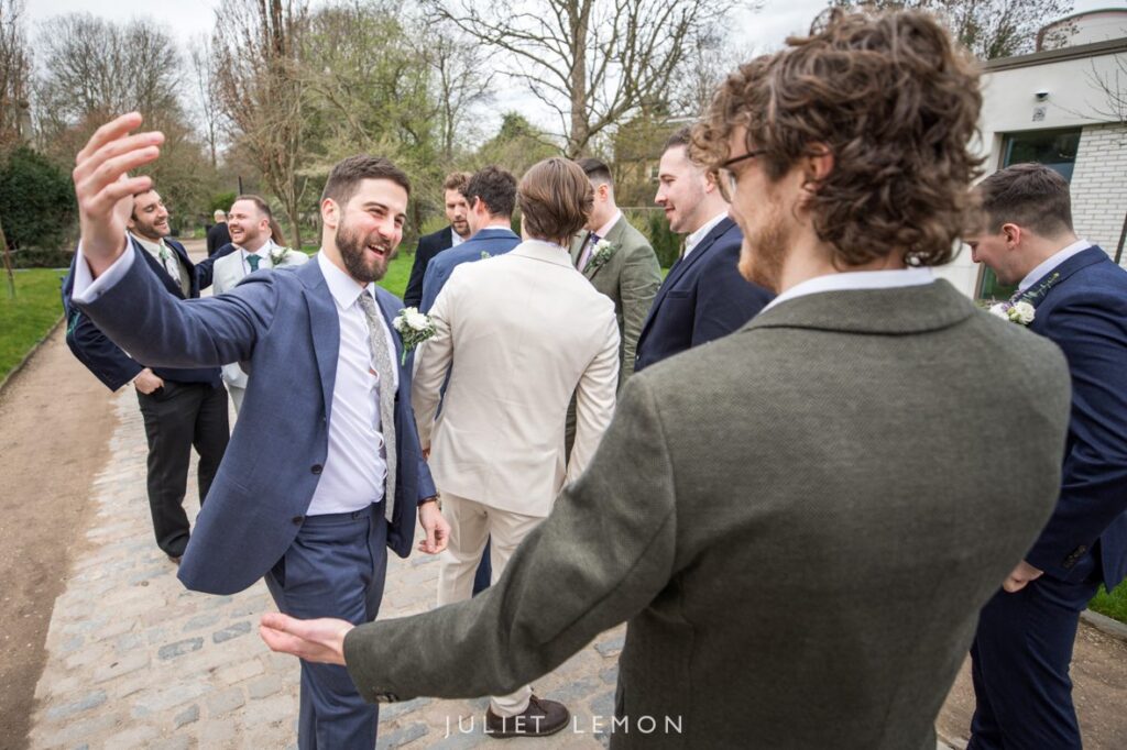 Candid wedding photography London of the groom laughing with his groomsmen outside the venue.