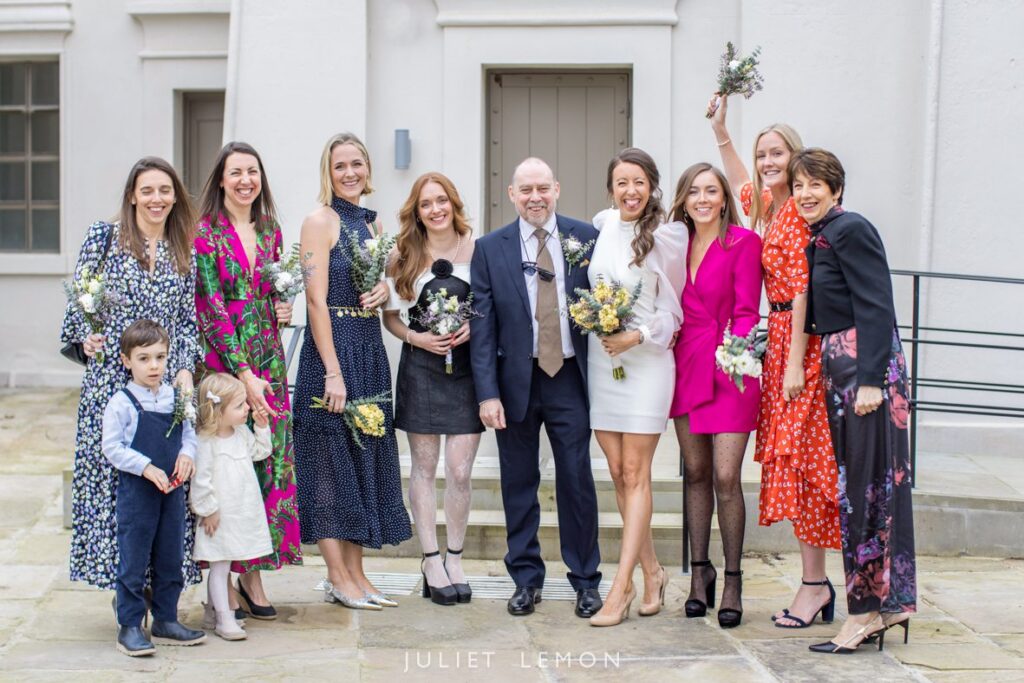Group portrait of the bridal party smiling outside the historic Stoke Newington wedding venue.