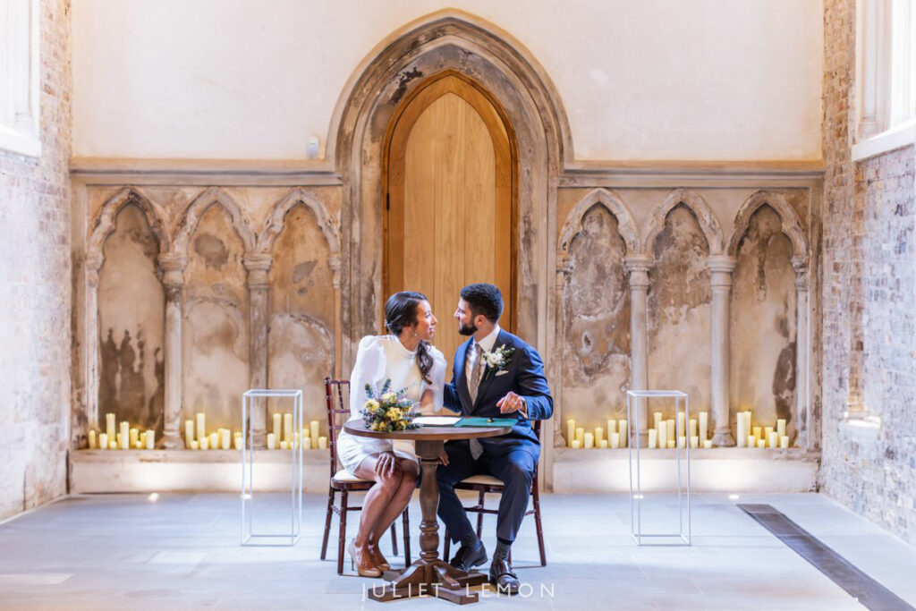 London wedding photographer captures the couple signing the register in the candlelit Abney Park Chapel.