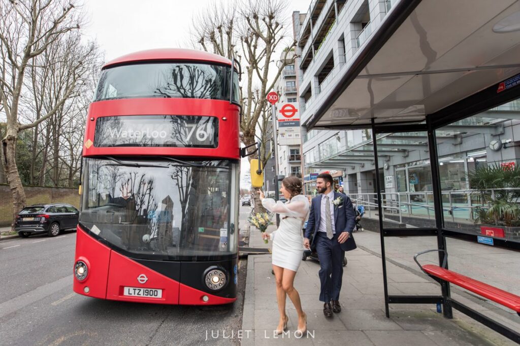 London wedding photographer capturing a bride and groom at a bus stop with a red London bus.