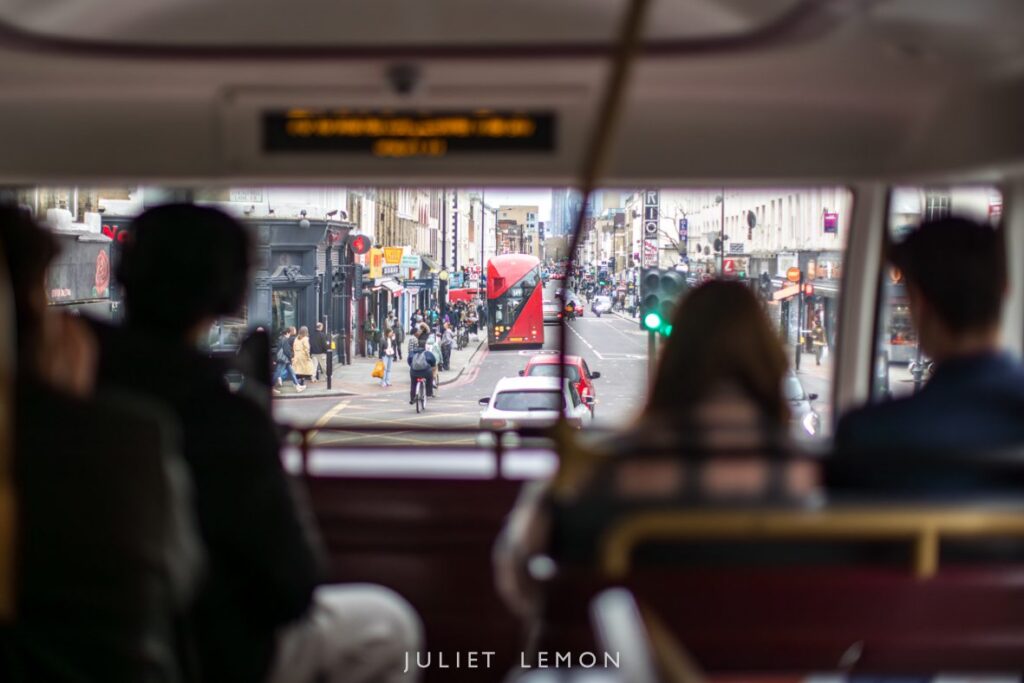 Candid wedding photography London: the view of city streets from the top deck of a wedding guest bus.