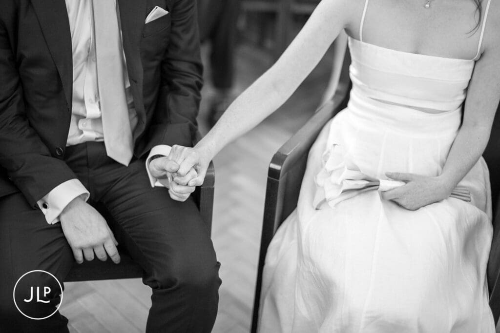 Close-up B&W shot of a bride and groom holding hands during their intimate London registry office wedding.