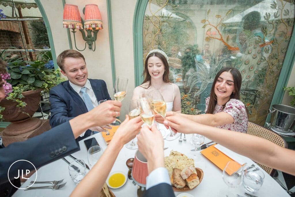 Bride and groom raising a glass for a champagne toast with guests at their London wedding reception.