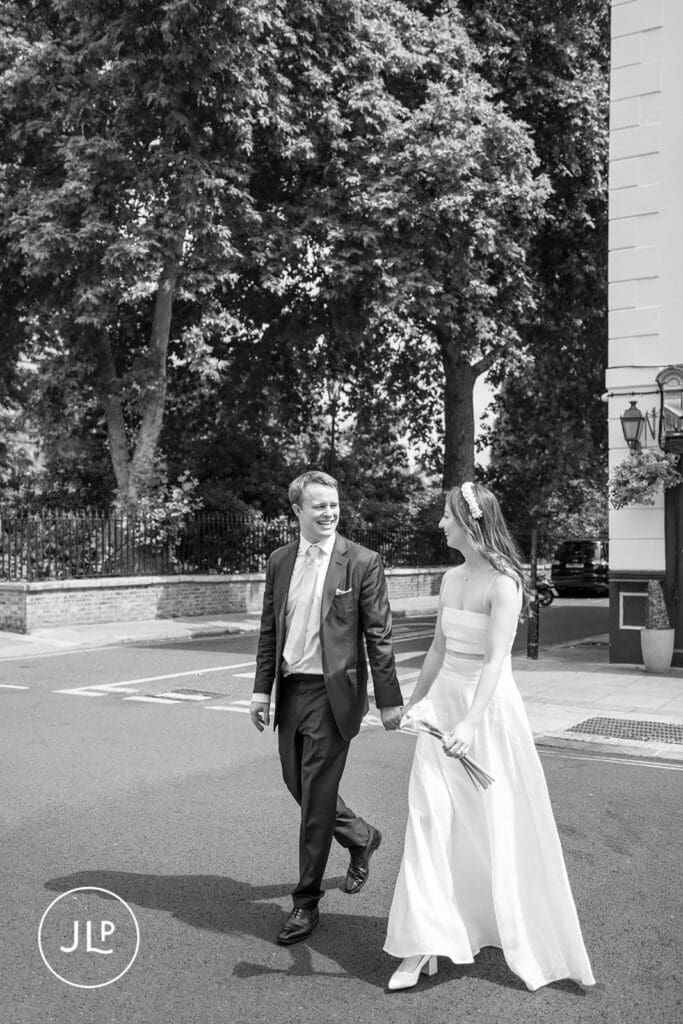 B&W shot of a bride and groom holding hands and walking, by a Chelsea Old Town Hall wedding photographer.