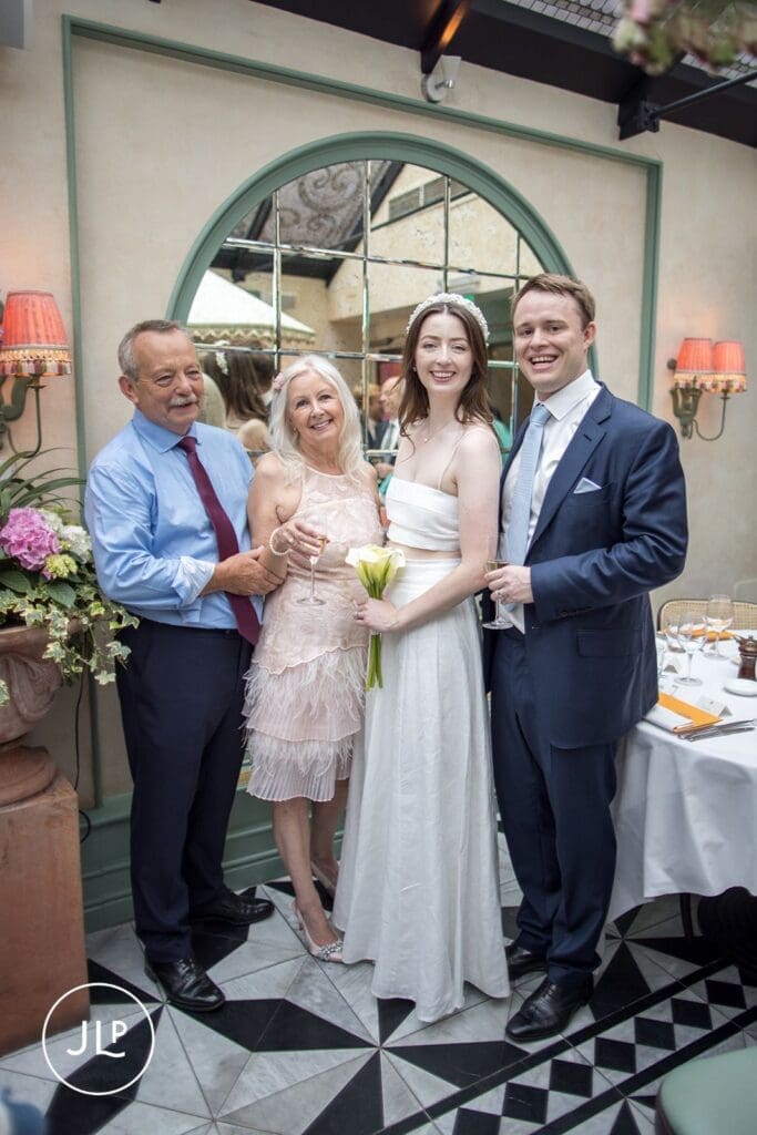 Smiling bride and groom posing with family guests inside a beautiful Chelsea wedding reception venue.