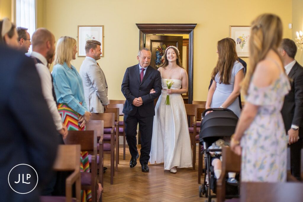 The bride walking down the aisle with her father at a stylish London registry office wedding.