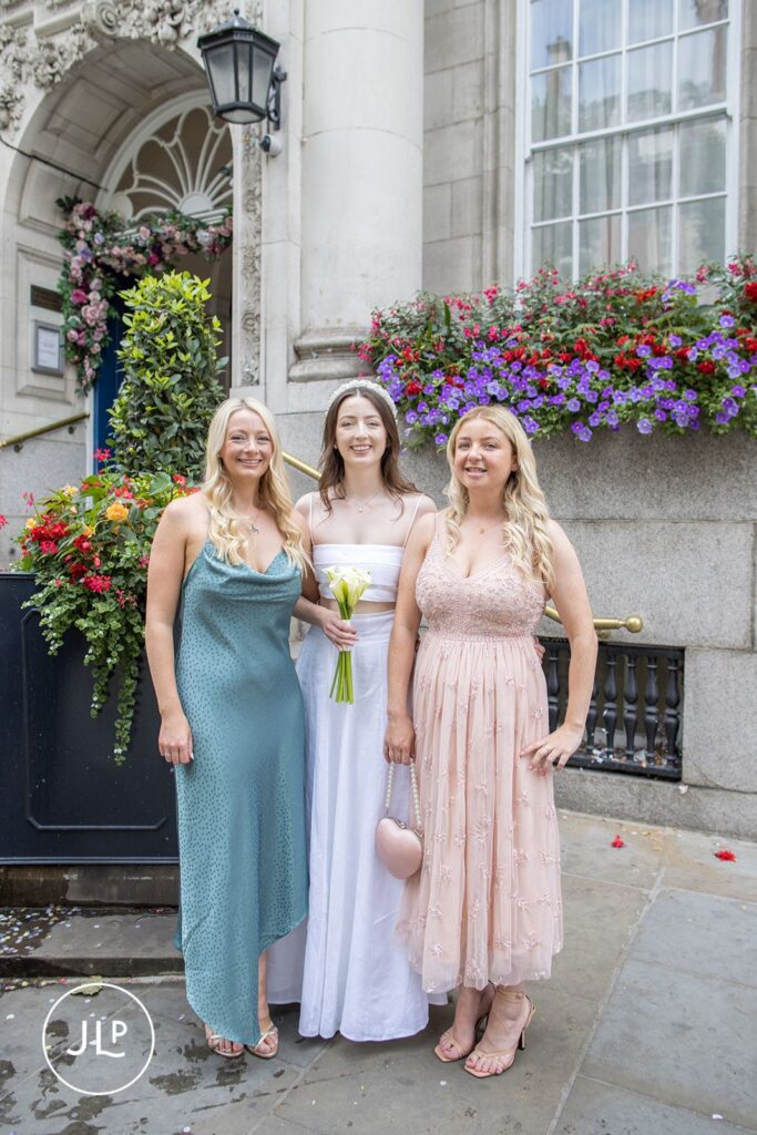 Bride Erin with her bridesmaids in front of the floral wedding entrance at Chelsea Old Town Hall.