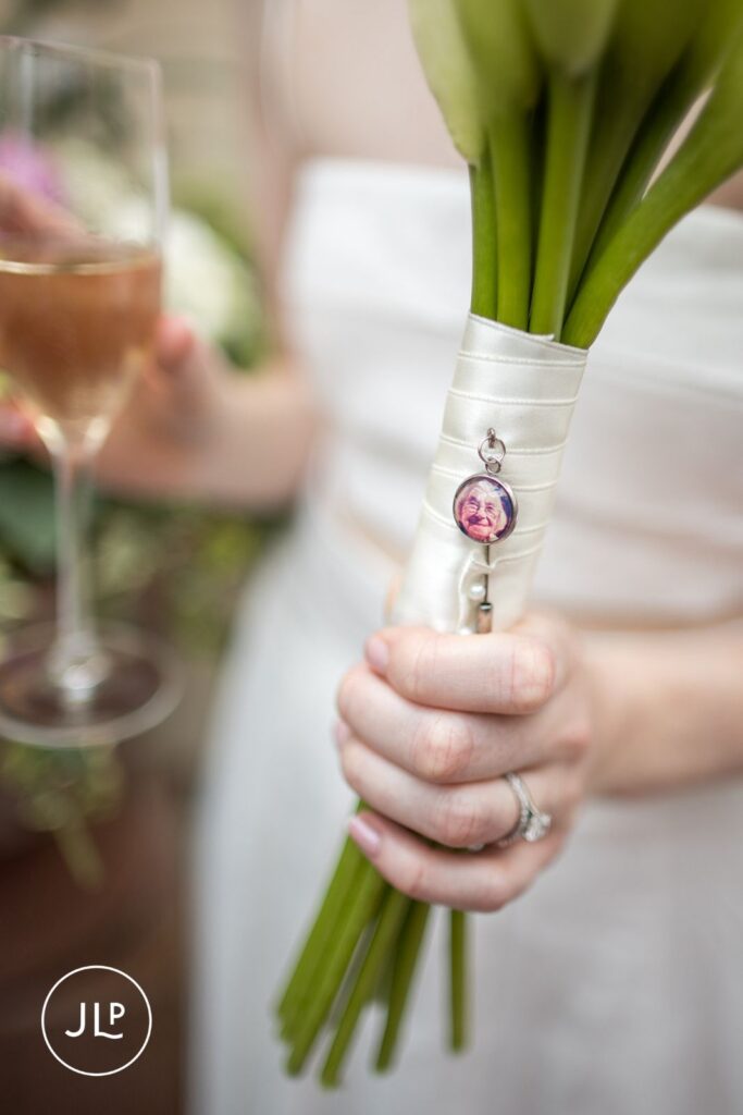 Close-up of a sentimental photo charm attached to a white calla lily bridal bouquet.