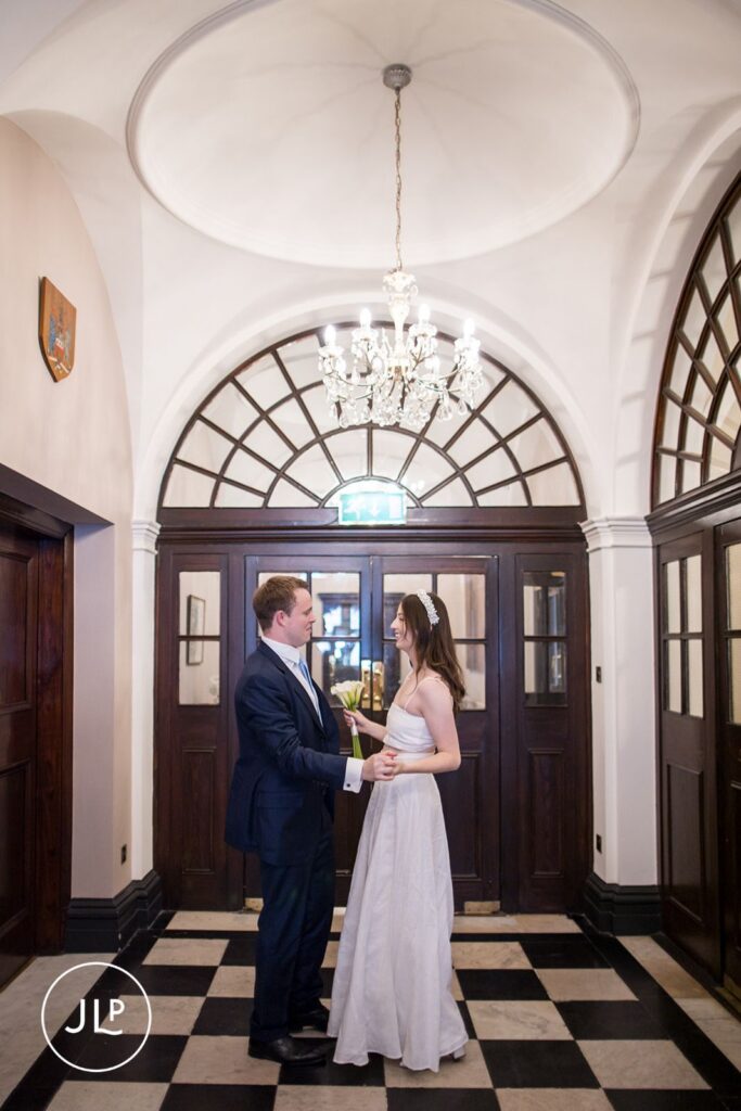 Newlyweds holding hands in the entrance hall of Chelsea Old Town Hall.