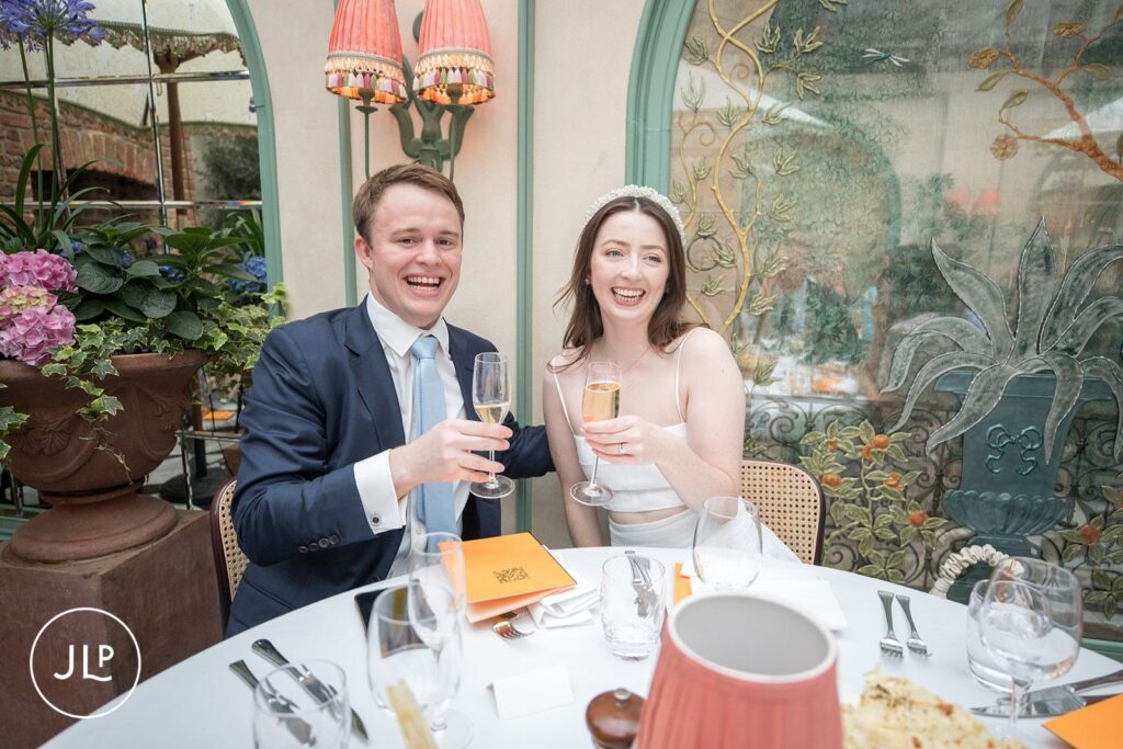 bride and groom toasting with champagne during their wedding breakfast at Daphne’s Chelsea.