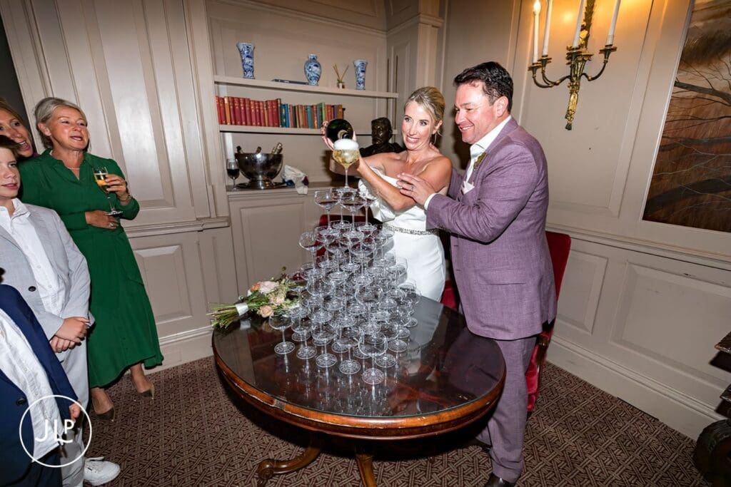 Bride and groom pouring champagne onto a glass tower at a luxury Buckinghamshire wedding reception.