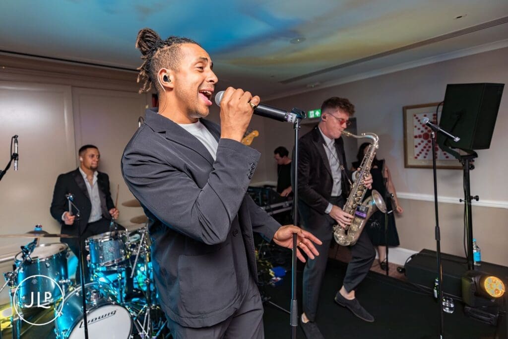 Energetic live wedding band performing with a singer and saxophonist at a Cliveden House reception party.
