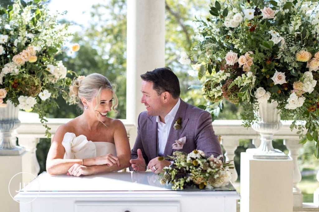 Smiling bride and groom sharing a laugh during their Cliveden Pavilion wedding ceremony.