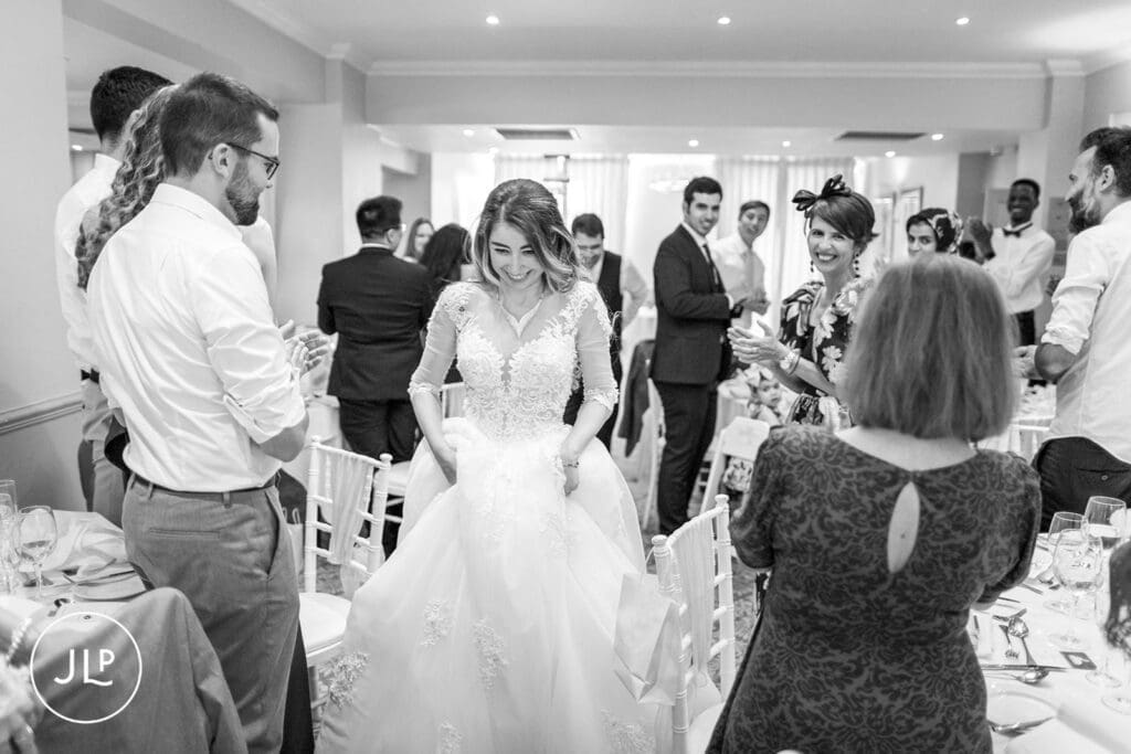 Black and white candid photo of a bride making her entrance to the reception.