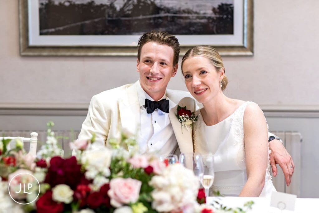 Candid moment of the bride and groom smiling at the top table.
