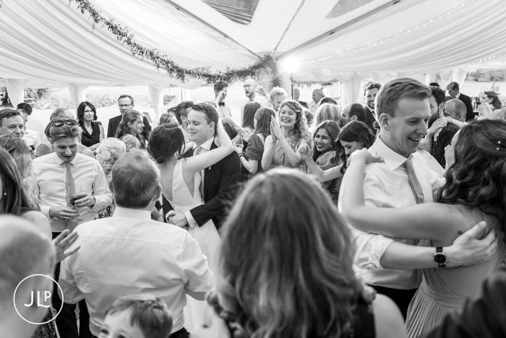 Joyful black and white candid of guests dancing at a luxury outdoor wedding Surrey.