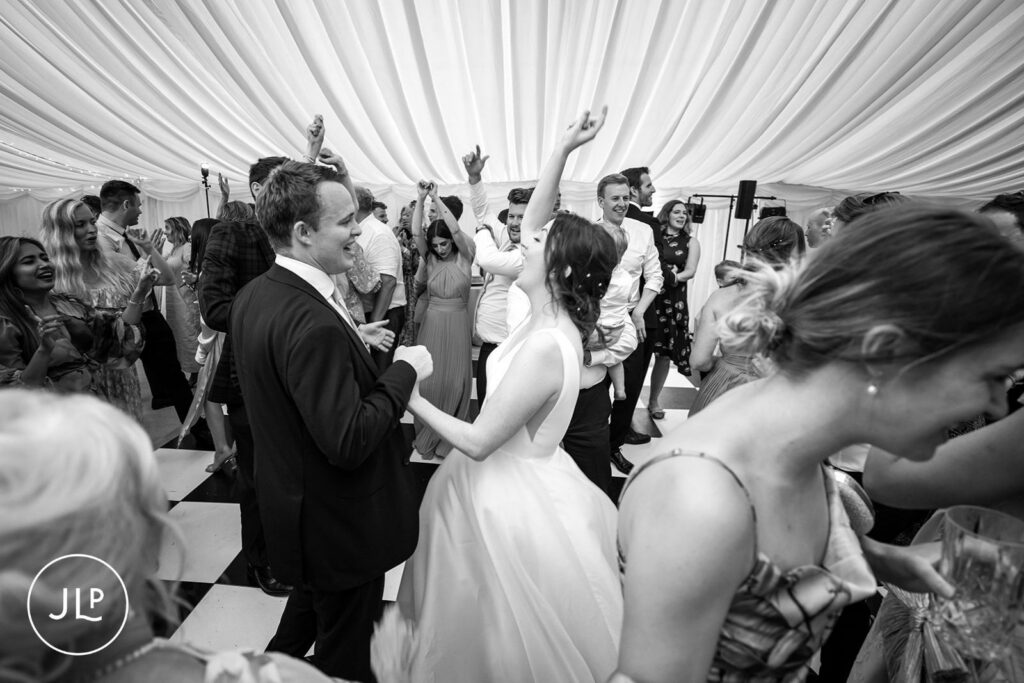 Bride and groom celebrating on the dance floor, captured by a Surrey marquee wedding photographer.