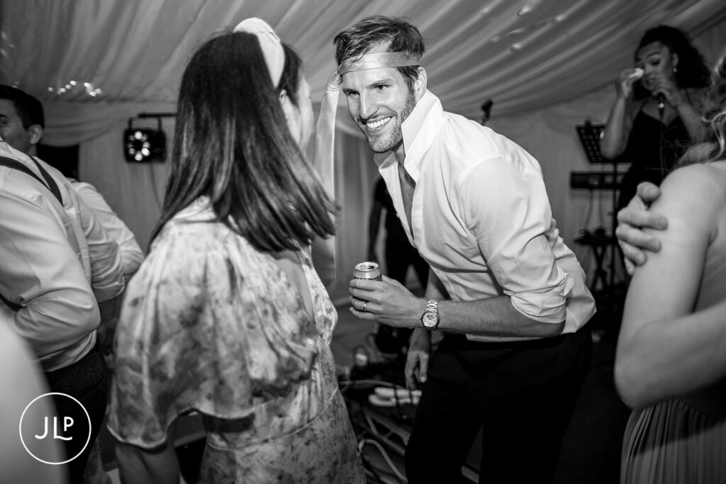 Fun moment of a guest with a tie around his head at a private estate wedding Surrey.