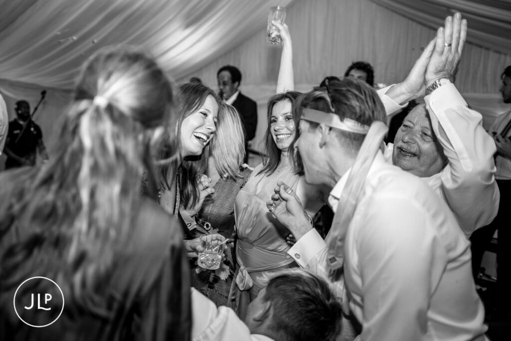 Emotional black and white candid of guests cheering during a luxury outdoor wedding Surrey.